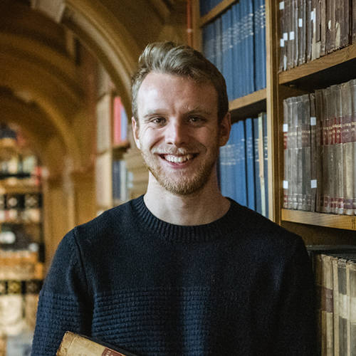 A student in an archive smiling at the camera.